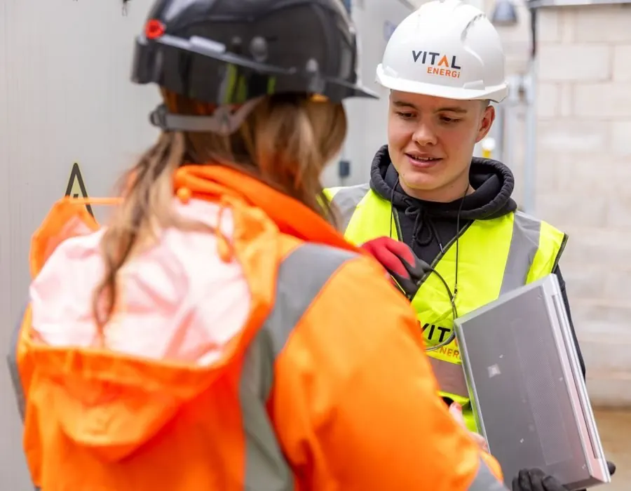 Two contractors reviewing job data on a laptop at a work site